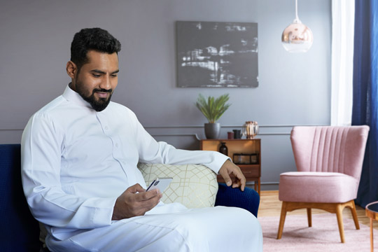 Resources/2/slider-New_Shutterstock-stock-photo-saudi-man-using-phone-at-home-sitting-at-sofa-in-living-room.jpg